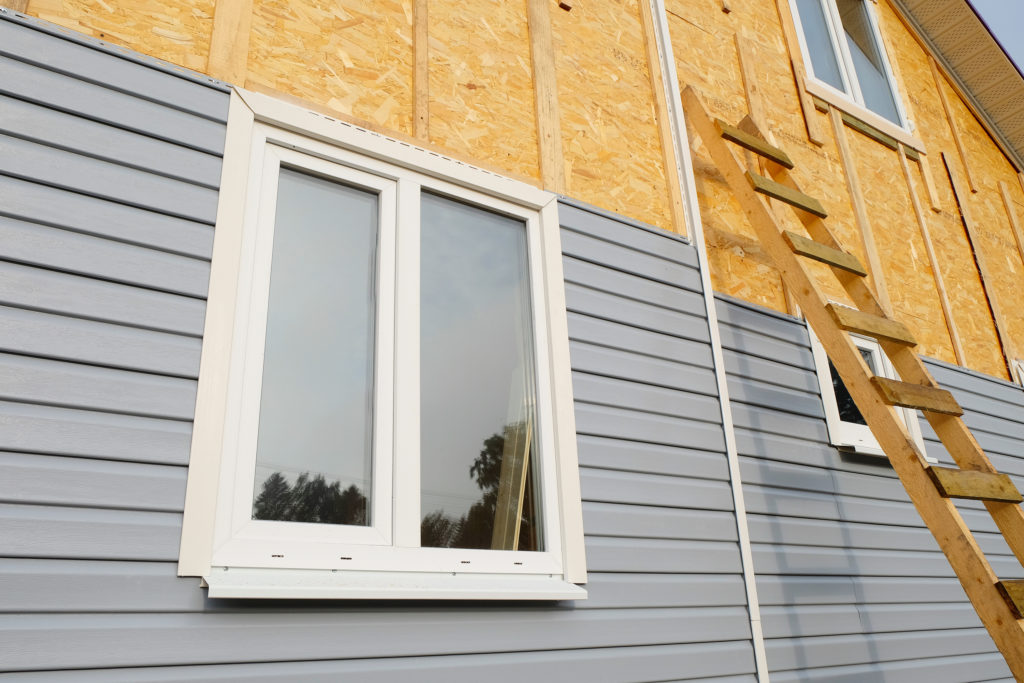 Siding covering the wall of a house under construction, with a ladder leaning against it